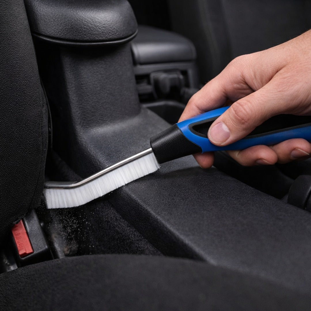 Person cleaning car seat with a brush and tool
