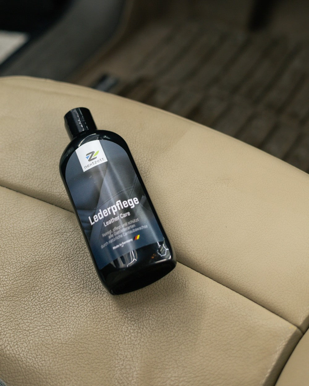 Bottle of nextzett Leather Care product on a beige leather surface